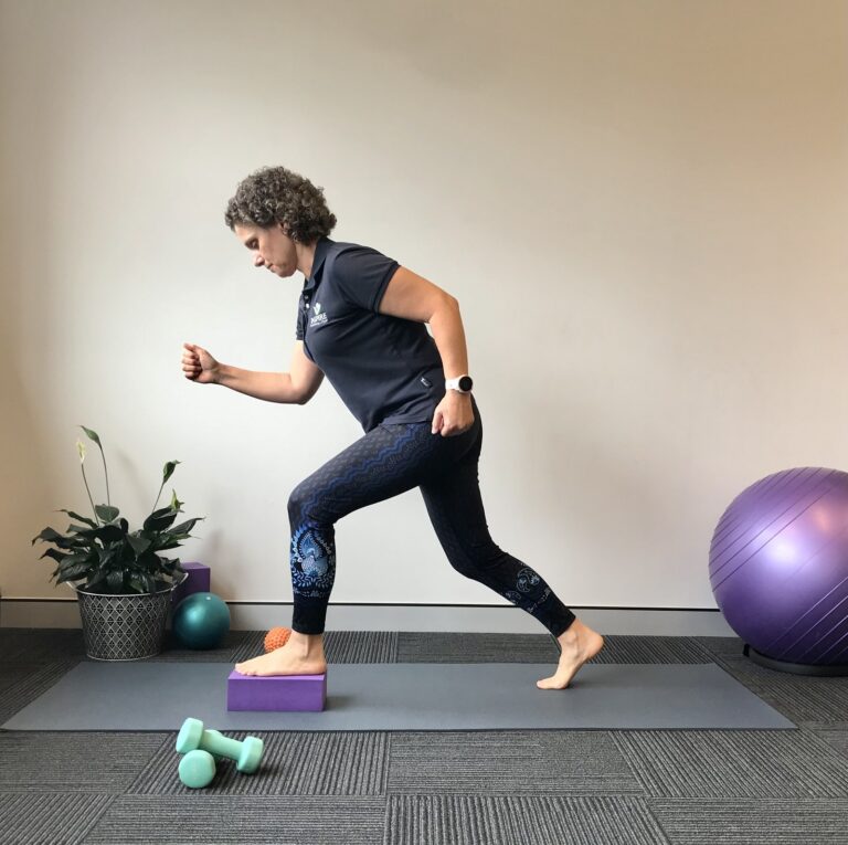 Leanne Hughes demonstrating a balance and strength exercise in a lunge position, with Pilates equipment around her